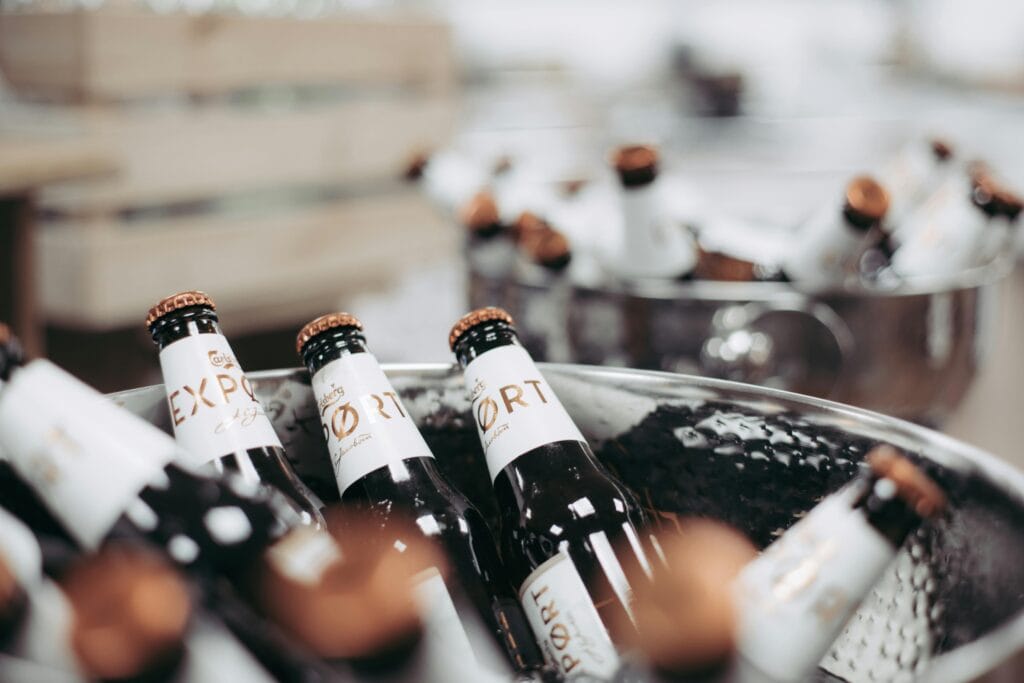 Close-up of chilled beer bottles in an ice bucket at a party. Perfect for beverage-themed images.
